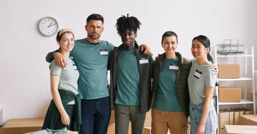 A diverse behavioral health crisis care team standing together in a support center, wearing matching name tags and green shirts. The team looks united and ready to respond to individuals in crisis with compassion and collaboration.