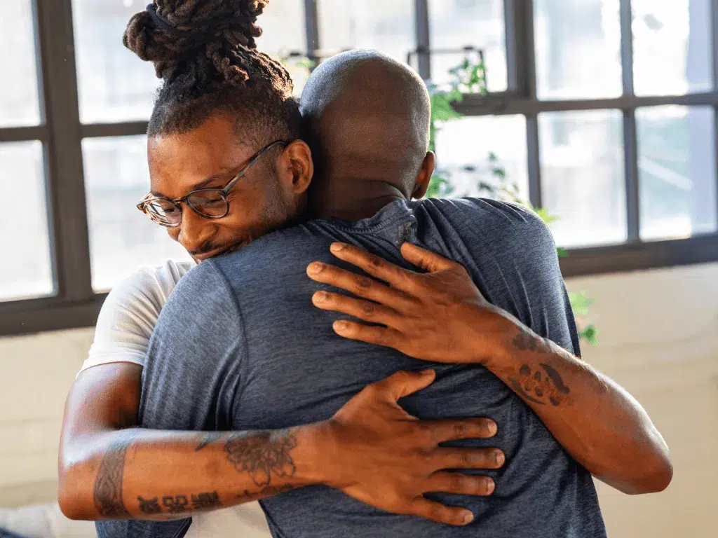 Two individuals embracing warmly in a bright, open space, conveying a sense of trust, support, and emotional connection.