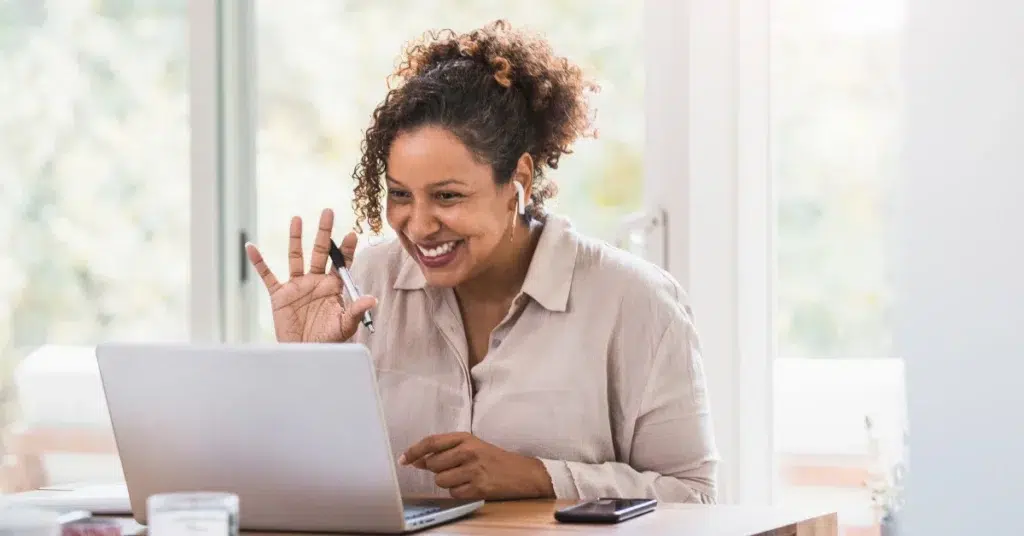 behavioral health therapist waving at her patient through a telehealth computer call